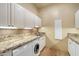 Well-equipped laundry room features white cabinets, stone countertops, and modern washer and dryer at 22610 N 80Th Pl, Scottsdale, AZ 85255