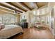 Expansive main bedroom features beamed ceilings, a cozy sitting area, and large windows overlooking lush greenery at 22610 N 80Th Pl, Scottsdale, AZ 85255