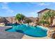 Gorgeous swimming pool surrounded by rocks, palms, and mature desert plants at 2272 W Jasper Butte Dr, Queen Creek, AZ 85144