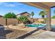 Lush backyard pool with rock feature, plants, and partially covered patio area at 2272 W Jasper Butte Dr, Queen Creek, AZ 85144