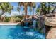Close-up of a rock waterfall flowing into the pool, adding a natural element to the backyard oasis at 30 W Sheffield Ave, Gilbert, AZ 85233