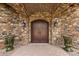 Inviting stone archway leads to a grand, double wooden front door with elegant sconces on either side at 3553 N Crystal Peak Cir, Mesa, AZ 85207