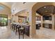 Kitchen bar featuring elegant arches, wooden stools, marble countertops, and seamless flow into a modern kitchen at 3553 N Crystal Peak Cir, Mesa, AZ 85207