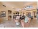 Open-concept living room with elegant chandelier, stone flooring, and seamless flow to kitchen at 3553 N Crystal Peak Cir, Mesa, AZ 85207