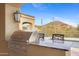 Outdoor kitchen with stainless steel grill, marble countertops, and comfortable seating with desert views at 3553 N Crystal Peak Cir, Mesa, AZ 85207