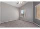 A simple bedroom featuring neutral carpet and paint, a ceiling fan, and a window with horizontal blinds at 3834 W Commonwealth Ave, Chandler, AZ 85226