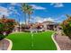 Beautiful backyard featuring a putting green, pool, gazebo, desert landscaping and mature palm trees at 4152 S Bandit Ct, Gilbert, AZ 85297