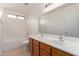 Bright bathroom with double sinks, large mirror, and white tiled shower-tub at 42796 W Wild Horse Trl, Maricopa, AZ 85138