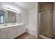 A bathroom with double sinks, white cabinets, a tub, and a glass shower enclosure at 45633 W Mountain View Rd, Maricopa, AZ 85139