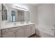 Well-lit bathroom with double sinks, white cabinets, a bathtub, and neutral finishes at 45633 W Mountain View Rd, Maricopa, AZ 85139