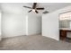Spacious main bedroom with carpeted floor, ceiling fan, and attached bathroom at 46123 W Sheridan Rd, Maricopa, AZ 85139