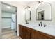 Stylish bathroom featuring double sinks, wood cabinets, modern fixtures, and view of the laundry space at 5221 N 24Th St # 103, Phoenix, AZ 85016