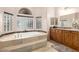 Bright bathroom featuring a soaking tub with glass block window and wooden vanity at 7804 S 15Th Ave, Phoenix, AZ 85041