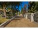 A long driveway is framed by green bushes and a white fence leading to the house at 7804 S 15Th Ave, Phoenix, AZ 85041