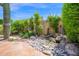 Landscaped backyard with rock garden, fountain feature, lush greenery, and patio at 7955 E Chaparral Rd # 73, Scottsdale, AZ 85250