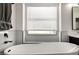 Close-up of a soaking tub beneath a window, featuring white marble tile and black trim at 8156 E Questa Rd, Scottsdale, AZ 85255