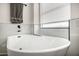 Close-up of a soaking tub beneath a window, featuring white marble tile and black trim at 8156 E Questa Rd, Scottsdale, AZ 85255