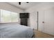 Bright bedroom with a window, wood flooring, and a large TV above a dark wood dresser at 8156 E Questa Rd, Scottsdale, AZ 85255