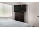 Bright bedroom includes a window, wood flooring, large TV, a ceiling fan, and sliding closet doors at 8156 E Questa Rd, Scottsdale, AZ 85255