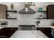 Up-close details reveal the stainless gas range and hood, tile backsplash, and shelves at 8156 E Questa Rd, Scottsdale, AZ 85255