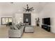Open-concept living room with modern ceiling fan, light hardwood floors, a black fireplace and comfortable gray sectional at 8156 E Questa Rd, Scottsdale, AZ 85255