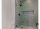 Modern shower stall with glass door, tiled walls, a black shower head, and built-in niche at 8156 E Questa Rd, Scottsdale, AZ 85255