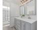 Bright bathroom featuring double sinks, decorative mirrors, and a shower with updated tile work at 921 N Oxford Ln, Chandler, AZ 85225