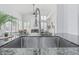 Close-up of a stainless steel kitchen sink with granite countertops and views of the bright and airy living room at 921 N Oxford Ln, Chandler, AZ 85225