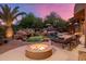 Backyard oasis featuring a pool with rock waterfall, firepit, chaise lounges, and lush desert landscaping at 9913 E Quarry Trl, Scottsdale, AZ 85262