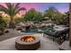 Backyard oasis featuring a pool with rock waterfall, firepit, chaise lounges, and mature landscaping at 9913 E Quarry Trl, Scottsdale, AZ 85262