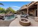 Expansive backyard featuring a pool, waterfall, fire pit, covered patio, and outdoor seating areas at 9913 E Quarry Trl, Scottsdale, AZ 85262