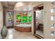 A luxurious bathroom features a jetted tub, a tiled shower, and decorative stained glass windows at 9913 E Quarry Trl, Scottsdale, AZ 85262