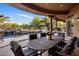 Inviting covered patio with an elegant outdoor dining table, plus views of the pool and waterfall feature at 9913 E Quarry Trl, Scottsdale, AZ 85262