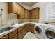 Convenient laundry room with wooden cabinets, tile countertops, stainless steel sink, and a washer and dryer at 9913 E Quarry Trl, Scottsdale, AZ 85262