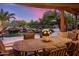 Covered patio with an outdoor dining area overlooking a pool with a rock waterfall feature at 9913 E Quarry Trl, Scottsdale, AZ 85262