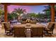 Back patio area featuring an outdoor dining set, a pool with a rock waterfall, and lush desert landscaping at 9913 E Quarry Trl, Scottsdale, AZ 85262
