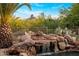 Scenic pool features a rock waterfall feature surrounded by mature desert landscaping and mountain views at 9913 E Quarry Trl, Scottsdale, AZ 85262
