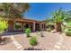 Relaxing backyard with a covered patio, desert landscape, and various trees and plants at 13052 W Mine Trl, Peoria, AZ 85383