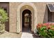 Arched entrance to an outdoor patio with desert landscaping, view of interior, and front door at 13052 W Mine Trl, Peoria, AZ 85383