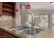 Kitchen island with double sink, granite countertops, stainless steel faucet, and red pendant lighting at 13052 W Mine Trl, Peoria, AZ 85383