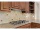 Gas cooktop on granite countertop with tile backsplash and dark wood cabinetry at 13052 W Mine Trl, Peoria, AZ 85383