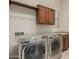 Modern laundry room with front loading washer and dryer and wood cabinets at 13052 W Mine Trl, Peoria, AZ 85383