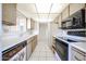 Galley kitchen featuring tile backsplash, white appliances, and light wood cabinets at 13618 N 98Th Ave # C, Sun City, AZ 85351