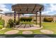 Shaded pergola on a brick and artificial turf base offers a tranquil outdoor relaxation spot in the backyard at 14674 W Pasadena Ave, Litchfield Park, AZ 85340