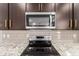 Close up view of microwave and stove with stainless steel appliances and granite countertops at 17437 W Via De Luna Dr, Surprise, AZ 85387