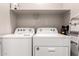 Bright laundry room includes shelving above the modern, white washer and dryer at 17437 W Via De Luna Dr, Surprise, AZ 85387