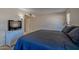 Comfortable bedroom with a blue comforter, a television, and soft lighting for relaxation at 17668 N Del Webb Blvd, Sun City, AZ 85373