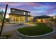 A well-manicured backyard with artificial turf, a fire pit, and a paver patio under a colorful twilight sky at 17831 W Mission Ln, Waddell, AZ 85355
