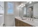 Bathroom features a double sink vanity, framed mirror, and window with plantation shutters at 17831 W Mission Ln, Waddell, AZ 85355