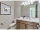 Stylish powder room features a wood vanity, modern fixtures, a framed print, and a neutral color palette at 17831 W Mission Ln, Waddell, AZ 85355